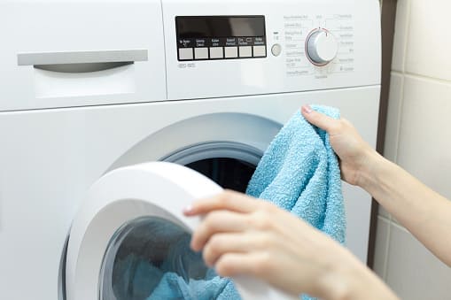 personne qui sort une serviette du lave-linge